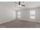 Bright bedroom featuring neutral walls, carpet flooring, a ceiling fan, and two windows at 52680 W Meadow Green Rd, Maricopa, AZ 85139