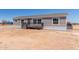 Single-story home with gray siding, covered porch, and desert surroundings at 52680 W Meadow Green Rd, Maricopa, AZ 85139