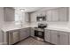 Charming kitchen featuring stainless steel appliances, gray cabinetry, and quartz countertops at 52680 W Meadow Green Rd, Maricopa, AZ 85139