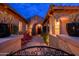 Home's front entrance features a brick walkway, stone facade, and gated courtyard with seating at dusk at 5428 E Windstone Trl, Cave Creek, AZ 85331