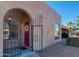 Charming stucco house with a red front door, secure gated entrance, and desert landscaping at 6819 E Sheena Dr, Scottsdale, AZ 85254