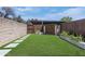 Green backyard with storage shed, stepped stone path, brick wall and wooden fence under a blue sky at 8135 N Central Ave # 1, Phoenix, AZ 85020
