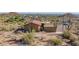Desert landscape with a home featuring a red-tile roof and multiple outbuildings, a mix of modern and traditional construction at 8752 E Range Rider Trl, Mesa, AZ 85207