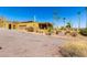 Tan home featuring a gravel drive, two car garage, desert landscaping, and a covered patio, set beneath a bright blue sky at 8752 E Range Rider Trl, Mesa, AZ 85207
