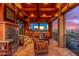 Covered patio has stone fireplace, outdoor kitchen, TV, beautiful Arizona sunset views, and seating at 8752 E Range Rider Trl, Mesa, AZ 85207