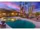 Backyard featuring pool, patio, and desert landscaping with cacti, succulents, and palm trees beneath a colorful sunset at 8752 E Range Rider Trl, Mesa, AZ 85207