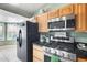 This kitchen has wooden cabinets, stainless steel microwave and oven with a black refrigerator at 8942 W Peck Dr, Glendale, AZ 85305