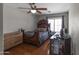 Bedroom featuring a ceiling fan, wood floors, desk and a window view at 9548 W Keyser Dr, Peoria, AZ 85383