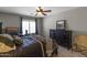 Comfortable bedroom with a ceiling fan, dark furniture, and a view to the front yard at 9548 W Keyser Dr, Peoria, AZ 85383