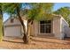 Single-story home with a two-car garage and desert landscaping, enhanced by a mature shade tree at 10735 W Bermuda Dr, Avondale, AZ 85392