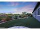 Expansive backyard with lush green turf, desert landscaping, and a retaining wall at 13236 W Montansoro Ln, Peoria, AZ 85383