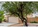Street view of two-story house, showing the garage and some landscaping with a large tree at 13443 W Crocus Dr, Surprise, AZ 85379