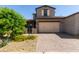 Charming two-story home showcasing a beige facade, tidy landscaping, and a brick paver driveway leading to a two-car garage at 14045 W Desert Flower Dr, Goodyear, AZ 85395