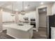 Bright kitchen featuring white cabinets, stainless steel appliances, an island with marble countertop, and pendant lighting at 14045 W Desert Flower Dr, Goodyear, AZ 85395