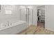 Bright bathroom featuring a soaking tub, glass enclosed shower, and an open walk-in closet with built-in shelving at 14435 W El Cortez Pl, Surprise, AZ 85387