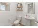 Stylish half bathroom with pedestal sink, shelving, and a window providing natural light at 14435 W El Cortez Pl, Surprise, AZ 85387