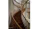 Curved wooden staircase with wooden railings and a dog sitting midway up the steps at 4018 E Adobe Dr, Phoenix, AZ 85050