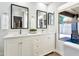 Bright bathroom featuring double sinks, framed mirrors, a window, and white cabinetry for ample storage at 4712 E Lone Cactus Dr, Phoenix, AZ 85050