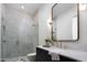 Modern bathroom with white tiled shower, glass enclosure, framed mirror, black cabinets, and marble countertop at 4864 E Lafayette Blvd, Phoenix, AZ 85018