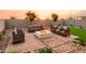 Inviting backyard features a cozy fire pit with ample seating, lush artificial grass, and a charming desert landscape at 4920 W Walatowa St, Laveen, AZ 85339