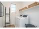 This laundry room features shelving, a window, and a front loading washer dryer at 4920 W Walatowa St, Laveen, AZ 85339