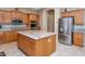 Bright kitchen with island, stainless steel refrigerator, and granite countertops at 6133 W Fetlock Ter, Phoenix, AZ 85083
