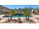 Inviting pool featuring a rock waterfall, desert landscaping, and a charming outdoor fireplace, perfect for relaxation at 6133 W Fetlock Ter, Phoenix, AZ 85083