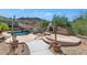 Backyard with a gorgeous pool featuring a rock waterfall, an outdoor fireplace, and mature cacti creating a serene retreat at 6133 W Fetlock Ter, Phoenix, AZ 85083