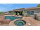 Backyard oasis with a pristine pool, a relaxing hot tub, desert landscaping, and an outdoor kitchen for entertaining at 6133 W Fetlock Ter, Phoenix, AZ 85083