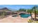 Beautiful backyard featuring a pool with a rock waterfall and spa, complemented by desert landscaping and stunning mountain views at 6133 W Fetlock Ter, Phoenix, AZ 85083