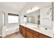 Bright bathroom showcasing a dual sink vanity, a large mirror, and a tub with shower at 664 E Windsor Dr, Gilbert, AZ 85296