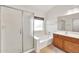 Bright bathroom featuring a soaking tub with shower, and a wooden vanity topped with white countertops at 664 E Windsor Dr, Gilbert, AZ 85296