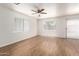 Spacious living room with gleaming wood floors, three large windows, and a modern ceiling fan with lighting at 8321 W Hughes Dr, Tolleson, AZ 85353