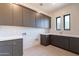 Laundry room with gray cabinets, patterned backsplash, sink, and two modern windows at 8366 E Old Paint Trl # 3, Scottsdale, AZ 85266