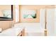 Bright bathroom features a large soaking tub with a framed mirror and beach themed art at 9248 E Blanche Dr, Scottsdale, AZ 85260