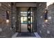 Open glass door showcasing a view into the home with stone walls and travertine tiled flooring at 9750 E Troon North Dr, Scottsdale, AZ 85262