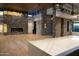 Open living space with stone fireplace, sleek lighting, and modern island with quartz countertops at 9750 E Troon North Dr, Scottsdale, AZ 85262