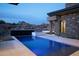 A luxurious pool with a water feature and stone accents complements the modern home design at 9750 E Troon North Dr, Scottsdale, AZ 85262