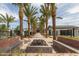 Inviting community entrance featuring palm trees, a stone pathway, fire pit, and comfortable benches at 10127 E Tillman Ave, Mesa, AZ 85212