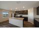 Open kitchen features granite counters, stainless appliances, dark cabinetry, island with sink, and natural light at 1074 W West Virginia Ave, Florence, AZ 85132