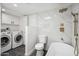 Dual purpose bathroom and laundry room featuring marble tile, tub, and laundry machine at 11079 N 110Th Pl, Scottsdale, AZ 85259