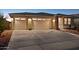 Well-lit home with a two-car garage, desert landscaping, and a wide concrete driveway at 12176 E Chevelon Trl, Gold Canyon, AZ 85118