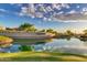 Scenic view of the 'Cantamia' community entrance, featuring a tranquil pond and lush greenery at sunset at 17179 S 174Th S Dr, Goodyear, AZ 85338