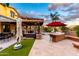 Expansive backyard featuring an outdoor kitchen, covered patio, seating, dining, and manicured lawn at 17363 W Lisbon Ln, Surprise, AZ 85388