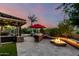 Outdoor entertainment area features a built-in grill, bar, fire pit, and lush landscaping at 17363 W Lisbon Ln, Surprise, AZ 85388