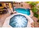 Backyard pool and jacuzzi with pavers, waterfall features, desert landscaping, and outdoor seating area at 17363 W Lisbon Ln, Surprise, AZ 85388