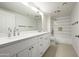 Bright bathroom featuring double sinks, white cabinetry, and a tiled shower with a glass door at 18873 N 94Th Way, Scottsdale, AZ 85255