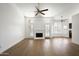 Cozy living room featuring hardwood floors, a fireplace, shuttered windows, and ceiling fans at 18873 N 94Th Way, Scottsdale, AZ 85255