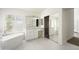 Bright bathroom featuring a soaking tub, dual vanity sinks, and a glass door leading to the closet at 18873 N 94Th Way, Scottsdale, AZ 85255