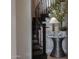 Close up of a stylish curved staircase with wrought iron railings and decorative table at 18927 N 101St St, Scottsdale, AZ 85255